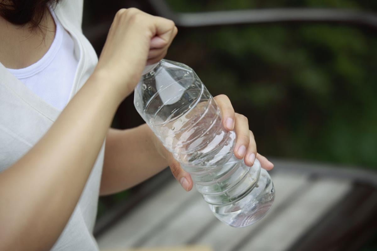 Person holding a plastic bottle of water
