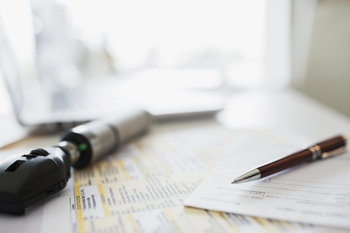 Physician's desk with otoscope and paperwork